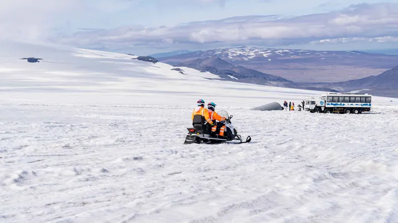 Double snowmobile on the Langjökull ice cap with the glacier truck behind on a Langjökull snowmobile and ice tunnel tour from Húsafell, Iceland