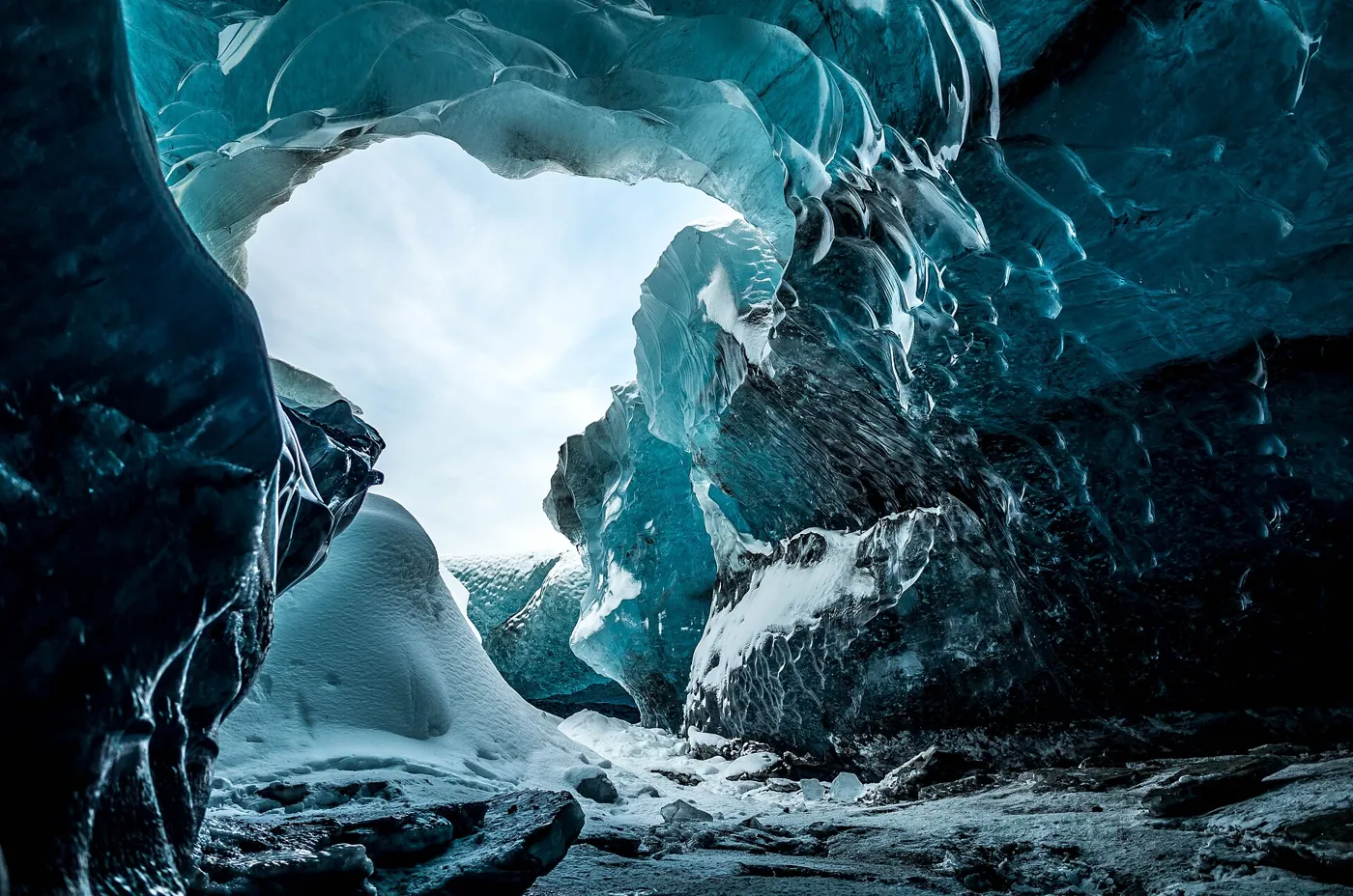 Daylight through a meltwater-carved arch in a natural glacier ice cave in Iceland, seen on an Iceland ice cave day tour