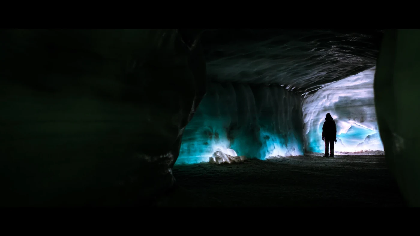 A visitor silhouetted in the lit man-made Into the Glacier tunnel inside Langjökull, an Iceland ice cave day tour that runs all year